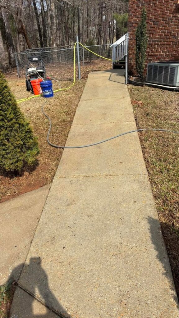 A clean concrete sidewalk after professional power washing by Plains Power Washing in Auburn, AL, with equipment visible.