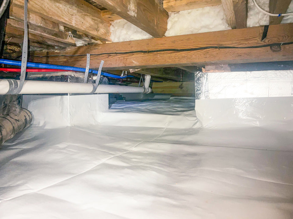 A clean crawl space with white vapor barrier and pipes, completed by Tidewater Home Improvement LLC in Hampton, VA.