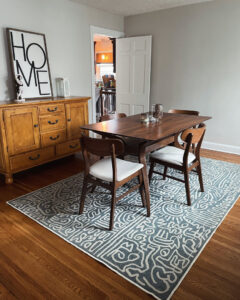 A tidy dining room with a wooden table, chairs, and a patterned rug, reflecting the excellent house cleaning by Cleans by Roseileen LLC in Louisville, KY.