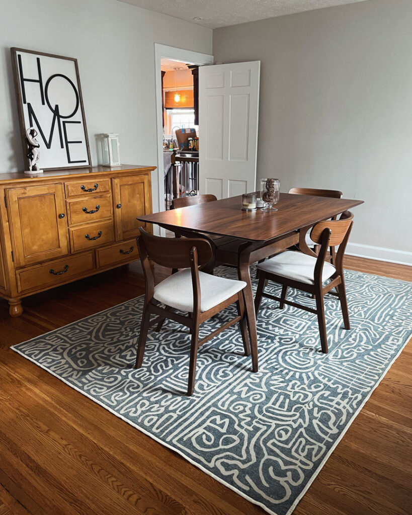 A tidy dining room with a wooden table, chairs, and a patterned rug, reflecting the excellent house cleaning by Cleans by Roseileen LLC in Louisville, KY.