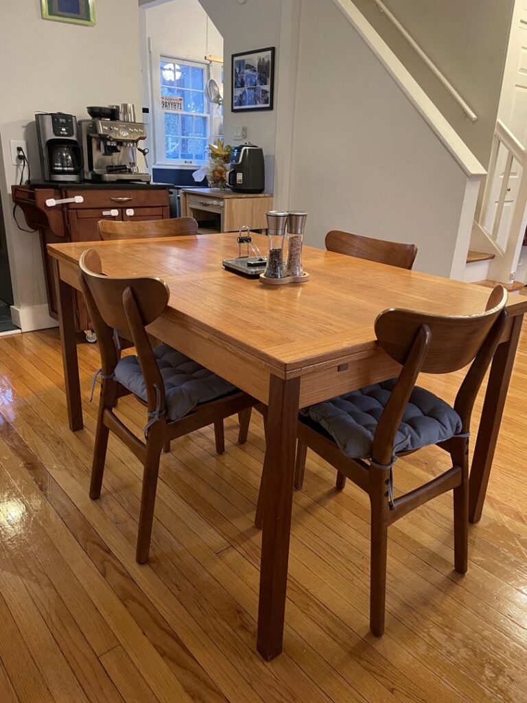 A polished wooden dining table with chairs in a clean home setting, showcasing the attention to detail by Cleans by Roseileen LLC in Louisville, KY.