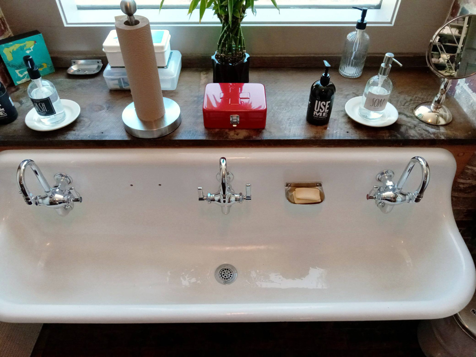 A meticulously clean white double sink with shining chrome faucets in a bathroom, cleaned by Peachy Clean Solutions in Saco, ME.