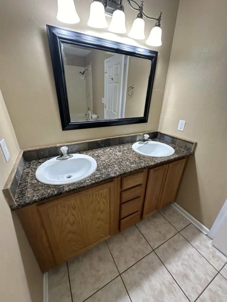 A clean double vanity with two sinks and a mirror in a bathroom, expertly cleaned by CLEAN That SHEET LLC in Jacksonville, FL.