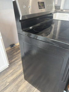 A clean black and stainless steel electric stove, viewed from the side, showing the meticulous cleaning provided by Claudia's Cleaning Services in Clarksville, TN.