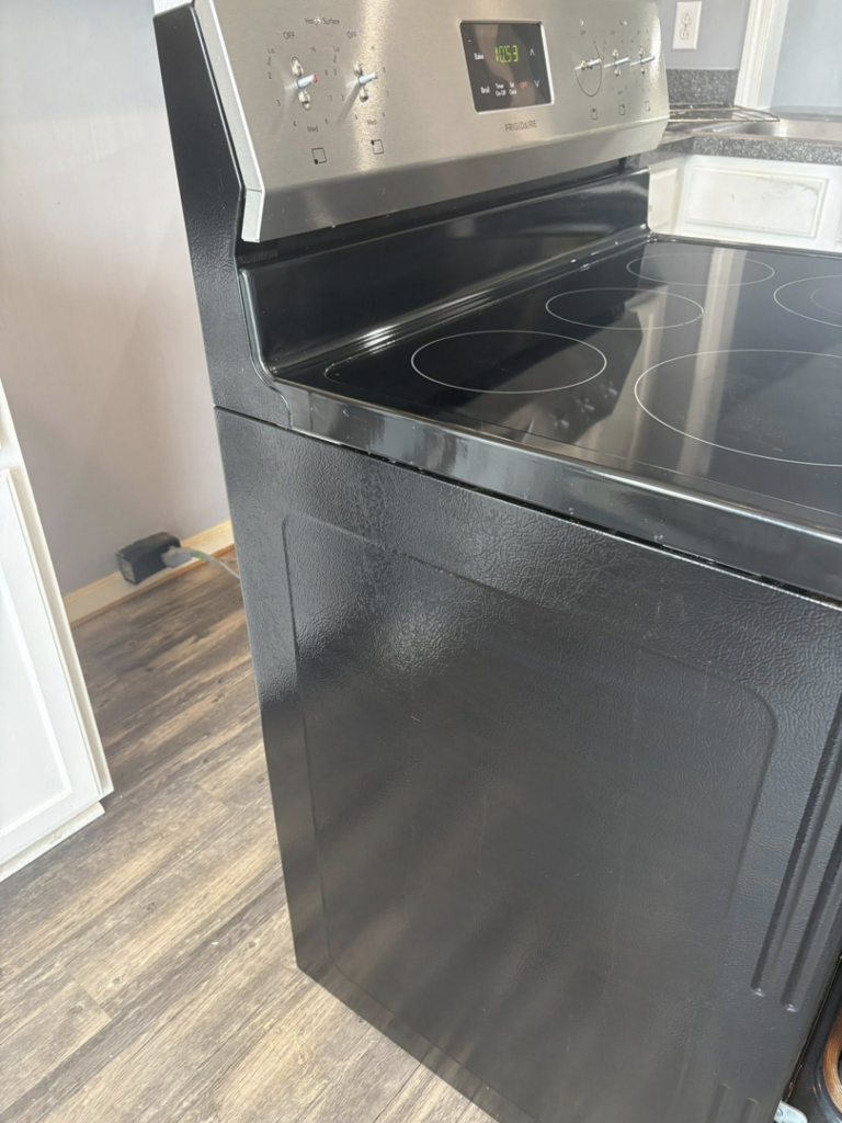 A clean black and stainless steel electric stove, viewed from the side, showing the meticulous cleaning provided by Claudia's Cleaning Services in Clarksville, TN.