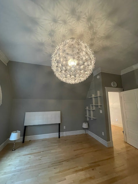 A clean, empty bedroom with hardwood floors and a unique light fixture by Straight Up Cleaning in South Portland, ME.