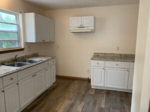 A clean, empty kitchen with white cabinets and granite countertops, demonstrating the thorough cleaning by Faye Cleaning Service LLC in Ankeny, IA.