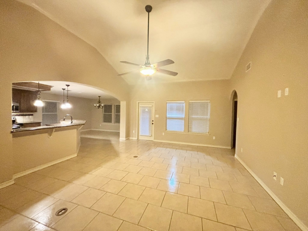 A bright and clean empty living room and kitchen area with tiled floors, professionally cleaned by Apryl's Cleaning Service in Corpus Christi, TX.