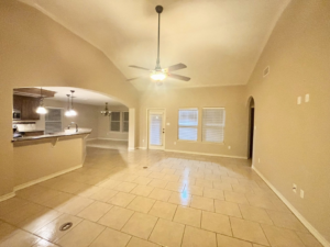 A bright and clean empty living room and kitchen area with tiled floors, professionally cleaned by Apryl's Cleaning Service in Corpus Christi, TX.