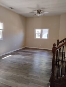 A clean, empty living room with light wood floors and neutral walls, perfect for move-in cleaning by Tessa's Cleaning Service in Chesapeake, VA.