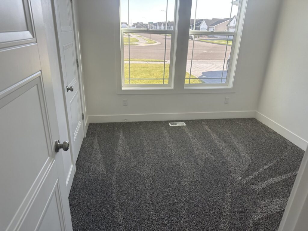 A clean, empty room with freshly vacuumed carpet, showcasing the results of Groove-By-Nature Cleaning in Idaho Falls, ID.