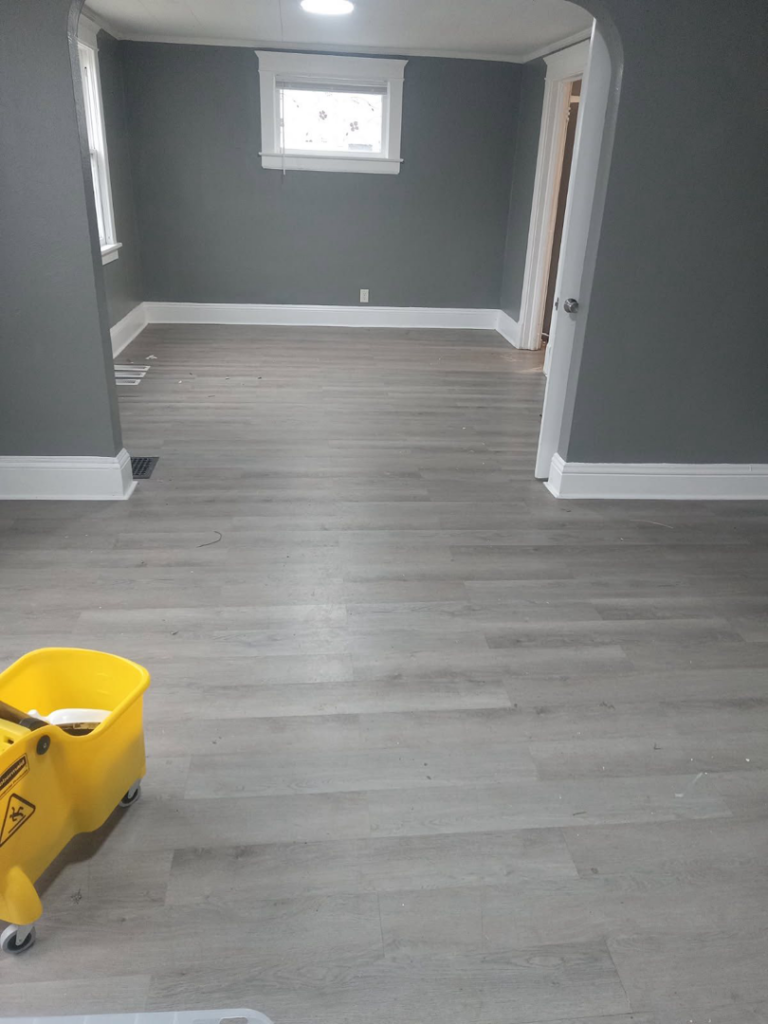 A clean, empty room with a mop bucket in the foreground, representing move-out cleaning services by Dacari's Helping Hands LLC in South Bend, IN.