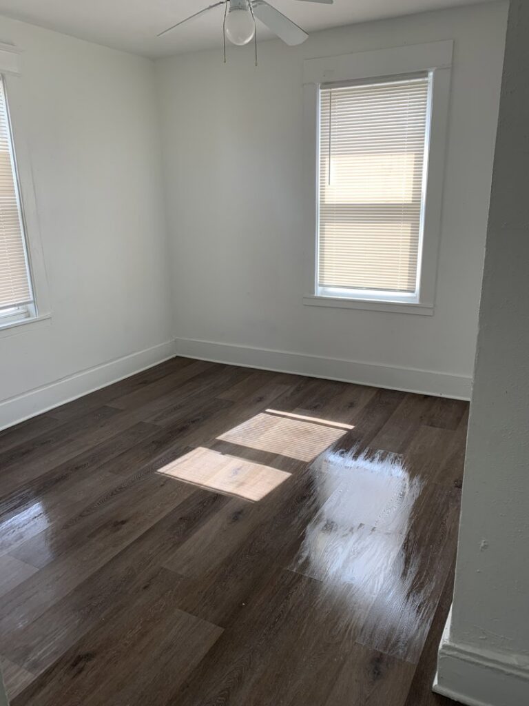 A clean, empty room with shiny hardwood floors, demonstrating the results of Faye Cleaning Service LLC in Ankeny, IA.