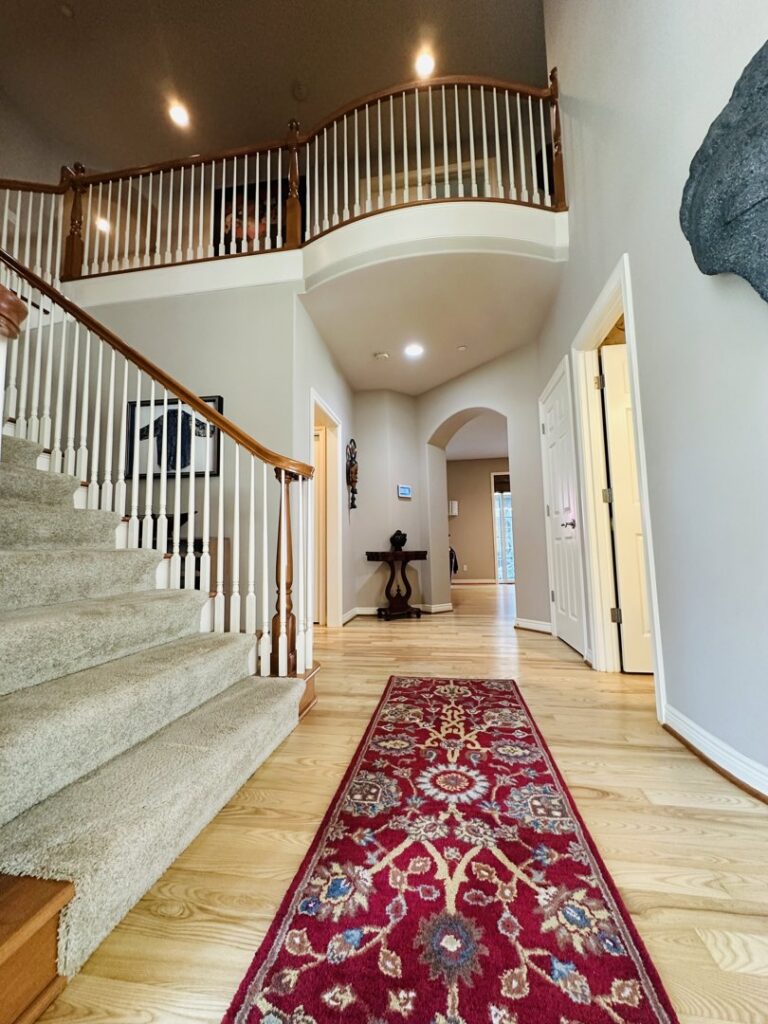 A pristine entryway featuring a grand staircase and polished hardwood floors, demonstrating the thorough cleaning by Quesada's cleaning services llc in Seattle, WA.