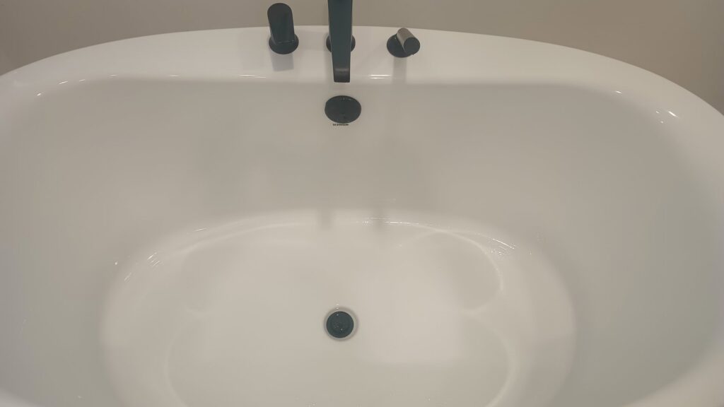 A pristine white freestanding bathtub with modern black fixtures, showcasing a clean bathroom by Carole's House Cleaning in Tempe, AZ.