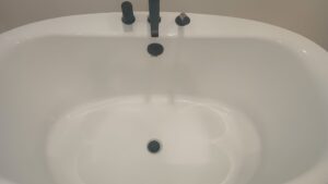 A pristine white freestanding bathtub with modern black fixtures, showcasing a clean bathroom by Carole's House Cleaning in Tempe, AZ.