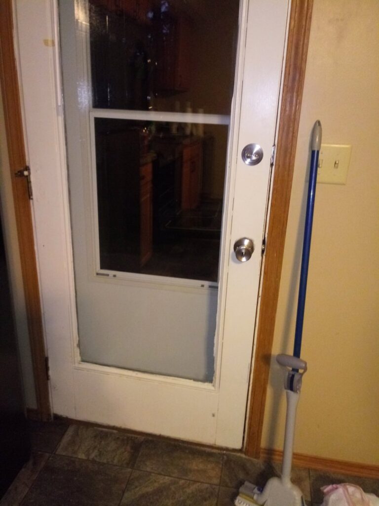 A clean glass door with a mop leaning nearby, suggesting professional cleaning services by L & G Cleaning Service in Aurora, CO.