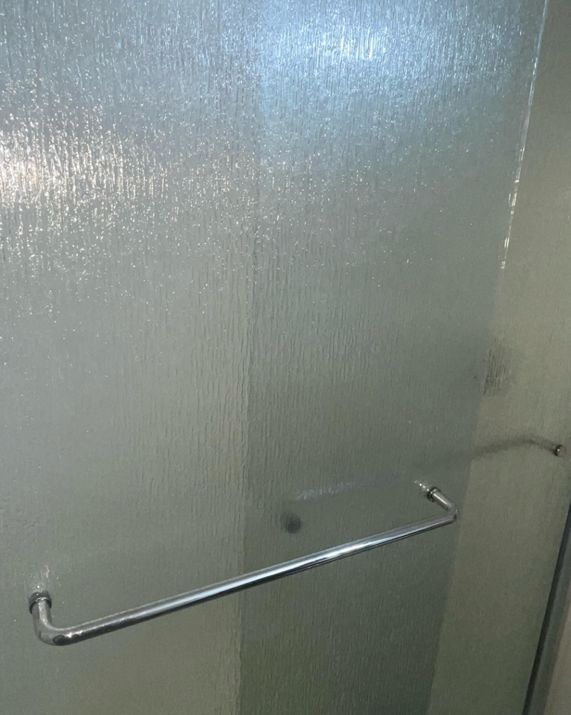 A pristine, clean textured glass shower door with a chrome handle by Stephie's From Dust To Glitter in Detroit, MI.