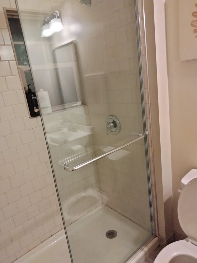 A clean glass shower stall with white tiles, demonstrating the quality bathroom cleaning by Perfection Cleaning in Kansas City, MO.