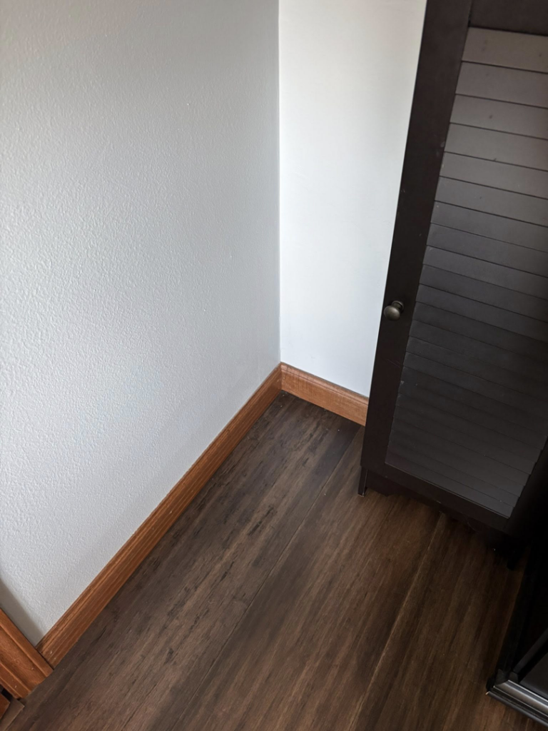 A perfectly clean hardwood floor and baseboard, showing the results of house cleaning by Spotless by Sam LLC in Green Bay, WI.