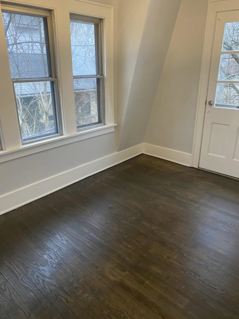 A freshly cleaned and polished hardwood floor in an empty room, ready for new occupants, by Kings and Queens of the Most High Cleaning Services in Akron, OH.