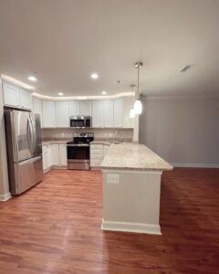 A sparkling clean kitchen with white cabinets, stainless steel appliances, and hardwood floors after a professional house cleaning by Rivas Molina's Cleaning LLC in Dundalk, MD.