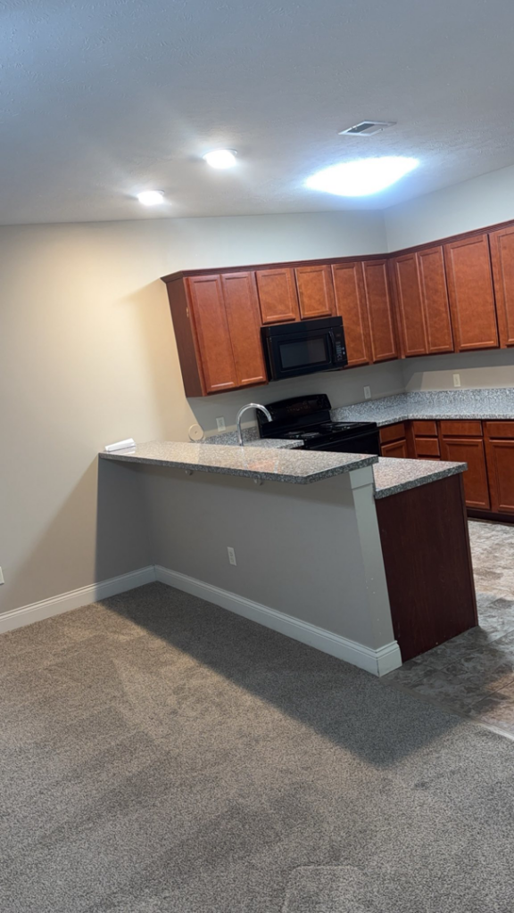 A wide view of a clean kitchen and adjacent carpeted living area, showcasing comprehensive house cleaning by NACleaning Co. in Omaha, NE.
