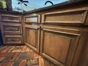 Clean wooden kitchen cabinets and a brick-patterned floor, showing a spotless area by Cleaning by Design LLC in Frederick, MD.