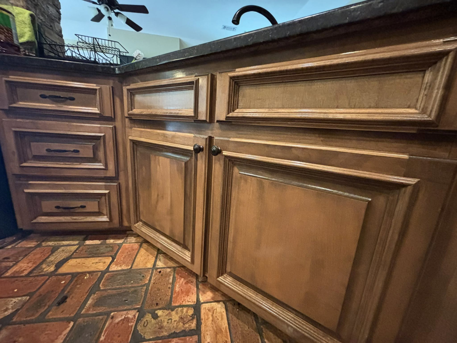 Clean wooden kitchen cabinets and a brick-patterned floor, showing a spotless area by Cleaning by Design LLC in Frederick, MD.