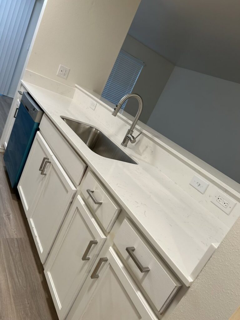 A spotless kitchen counter with a sink and white cabinets, cleaned by Martinez Cleaning Services in Kent, WA