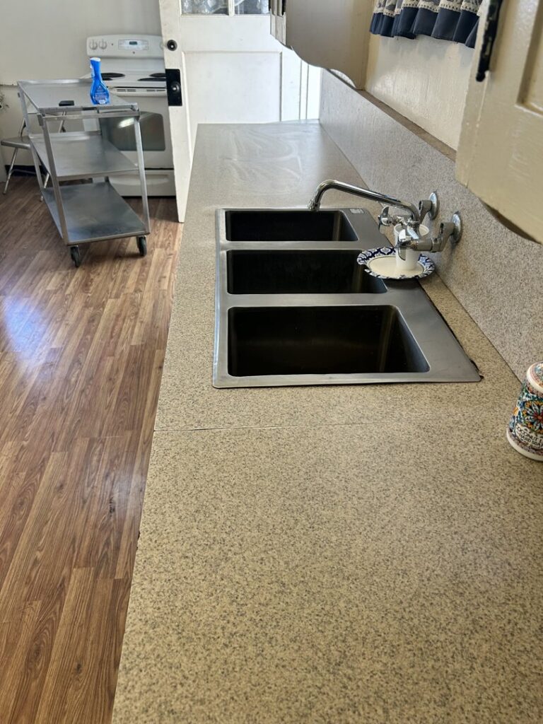 A clean kitchen counter with stainless steel sinks, sparkling after cleaning by Green Leaf Janitorial in Gilbert, AZ.
