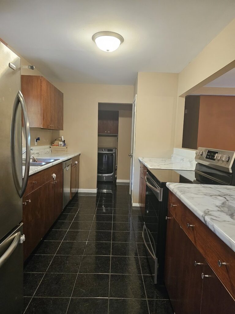 A meticulously cleaned kitchen with dark wood cabinets, black tiled floor, and stainless steel appliances by Way Too Bright Services LLC in Rockford, IL.