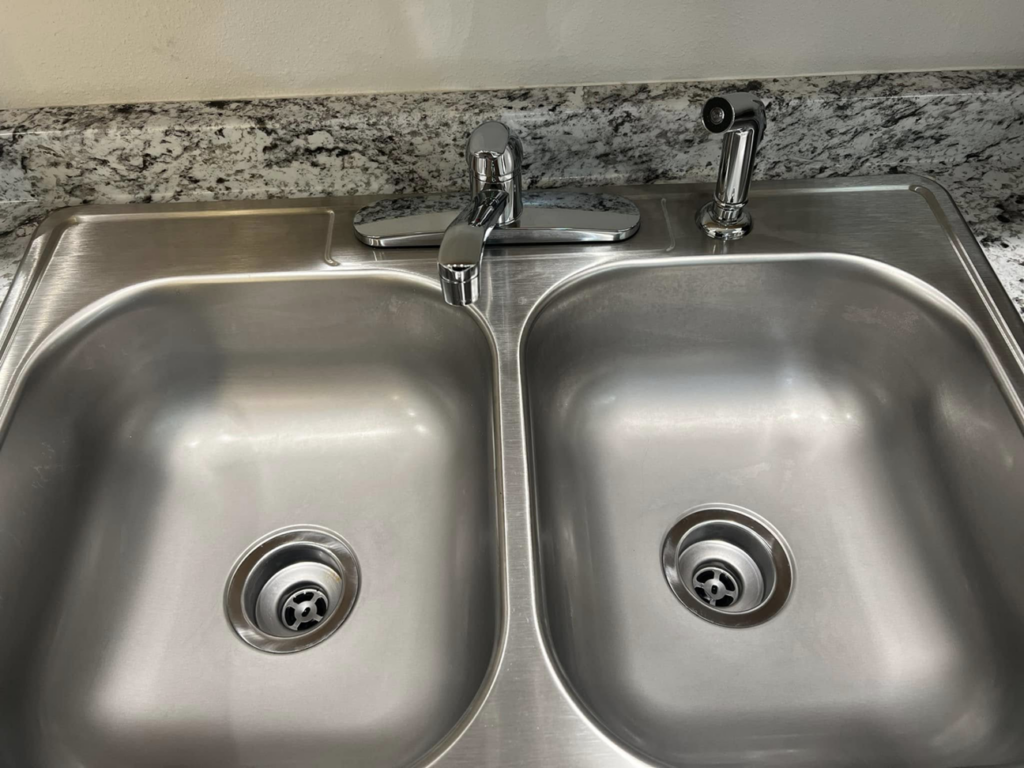 A sparkling clean stainless steel kitchen double sink after cleaning by V's Residential Cleaning Services in Tacoma, WA.
