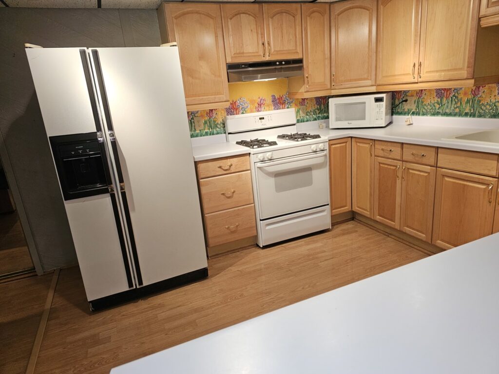 A sparkling clean kitchen with light wood cabinets and white appliances, demonstrating a house cleaning by Way Too Bright Services LLC in Rockford, IL.