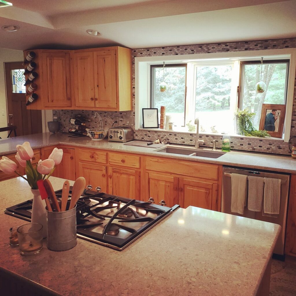 A clean kitchen with light wood cabinets, a tiled backsplash, and a gas range, professionally cleaned by A To Zen in Lansing, MI.