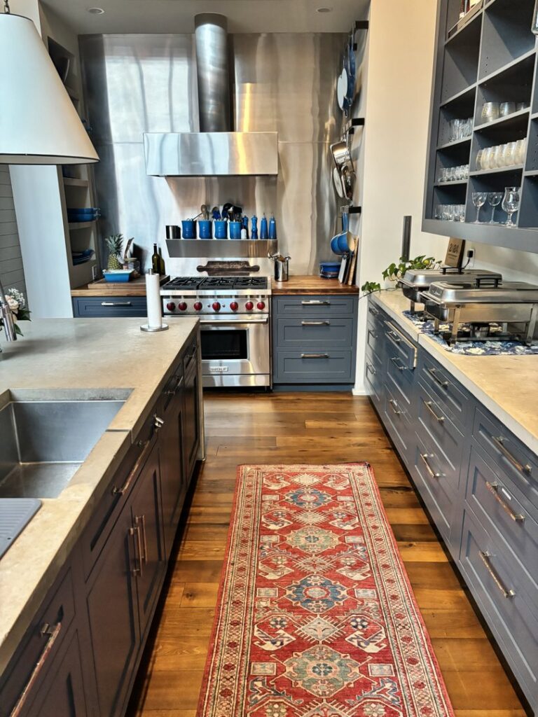A tidy kitchen featuring a long runner rug and stylish blue cabinets, cleaned by Bee Clean Solutions in Lexington, KY.