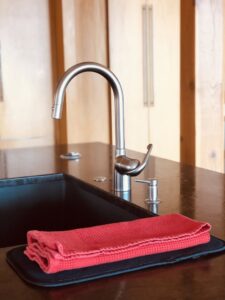 A clean kitchen sink with a neatly folded red towel, showcasing the attention to detail by Sudz Up Cleaning Company in Columbia, MO.