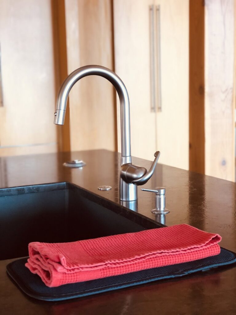 A clean kitchen sink with a neatly folded red towel, showcasing the attention to detail by Sudz Up Cleaning Company in Columbia, MO.
