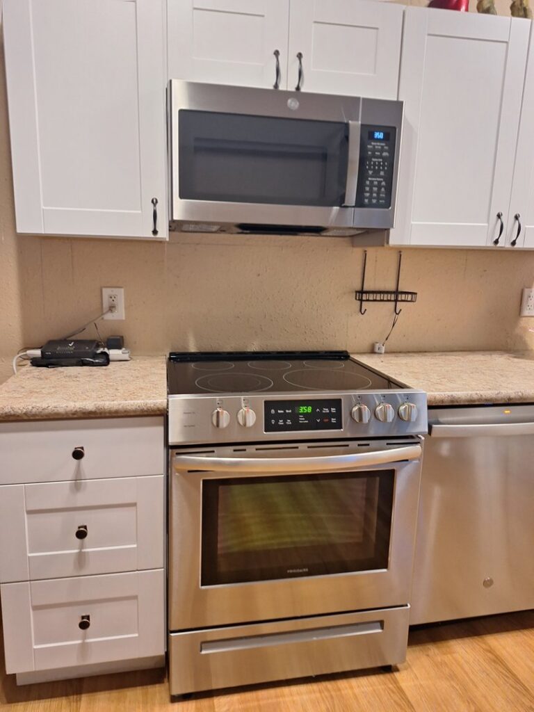 A bright and clean kitchen with white cabinets and stainless steel appliances, cleaned by Martinez Cleaning Services in Kent, WA