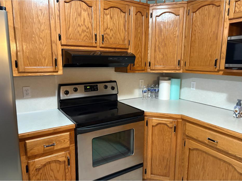 A spotless kitchen featuring clean wooden cabinets, a stainless steel stove, and tidy countertops by In Between Clean 2 in Greeneville, TN.