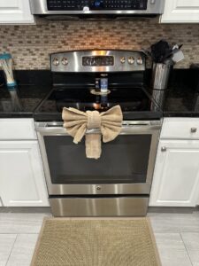 A meticulously cleaned kitchen stove with a decorative towel bow, a detail from Nichole's Cleaning Service in Fort Wayne, IN