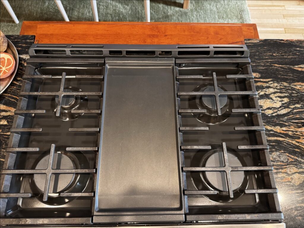 A close-up of a sparkling clean kitchen stovetop with grates, demonstrating professional cleaning by New Image Cleaning Service LLC in Richmond, VA.