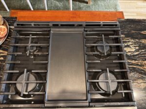 A close-up of a sparkling clean kitchen stovetop with grates, demonstrating professional cleaning by New Image Cleaning Service LLC in Richmond, VA.