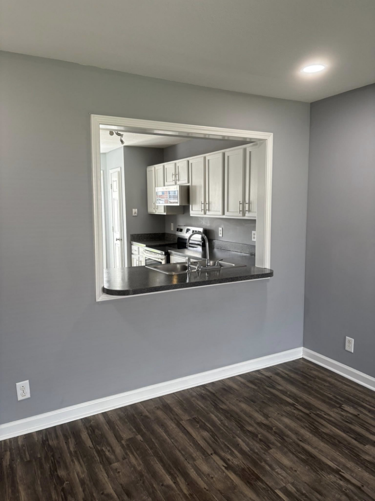 A clean and tidy kitchen, viewed through a pass-through window from the dining area, showcasing the excellent results from Claudia's Cleaning Services in Clarksville, TN.