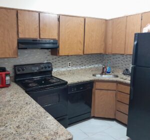 A clean kitchen featuring black appliances and wooden cabinets, by Whole New World Cleaning Service, LLC in Wilmington, DE