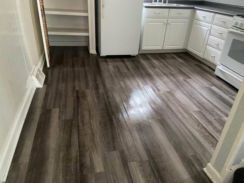 A clean kitchen featuring dark wooden floors and white cabinets, showcasing the results of Rivas Molina's Cleaning LLC in Dundalk, MD.