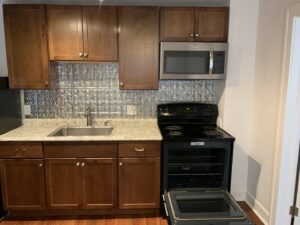 A clean kitchen with wooden cabinets, a black stove, and a microwave, demonstrating the quality cleaning by Faye Cleaning Service LLC in Ankeny, IA.