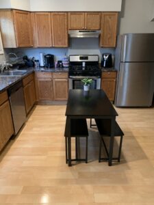 A clean kitchen with wooden cabinets, stainless steel appliances, and a dining table, showcasing the results of Faye Cleaning Service LLC in Ankeny, IA.