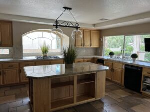 A clean kitchen with light wooden cabinets, granite countertops, and a central island, showcasing cleaning by JG Clean Solutions in Henderson, NV.