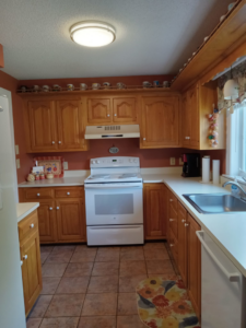 A bright and clean kitchen featuring wooden cabinets and white countertops, professionally cleaned by Peachy Clean Solutions in Saco, ME.
